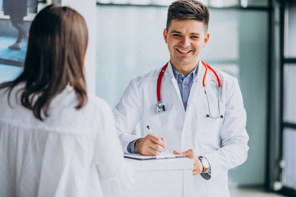 A smiling doctor in Dallas, TX, reviewing a patientu2019s medical records during a consultation.