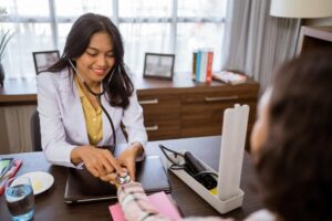 female-doctor-holding-patients-wrist-checking-heart-rate-with-stethoscope-sitting-examination-room